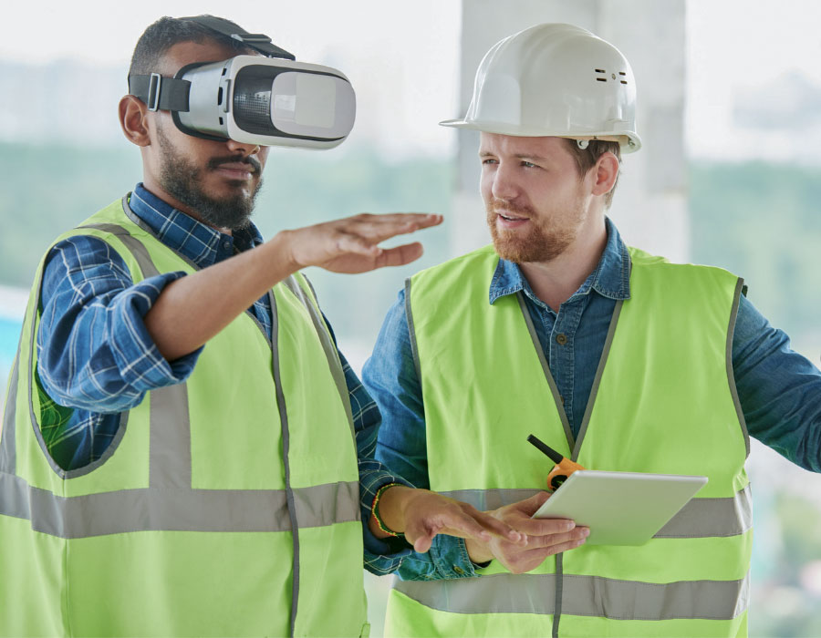 Two men wearing high vis, one wearing a VR headset